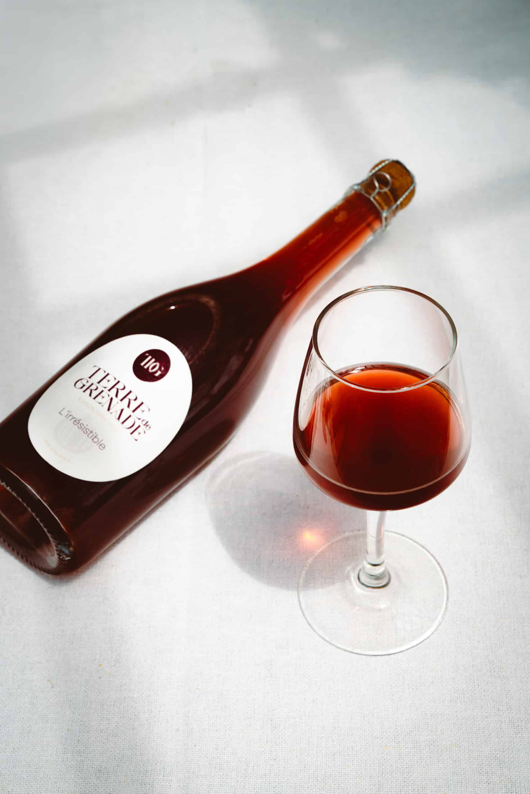 Wine glasses filled with red and rosé wine, with a bottle on a white table. 